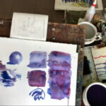 Painting on an artists easel with purples, blues and other colors displaying techniques for painting rocks.