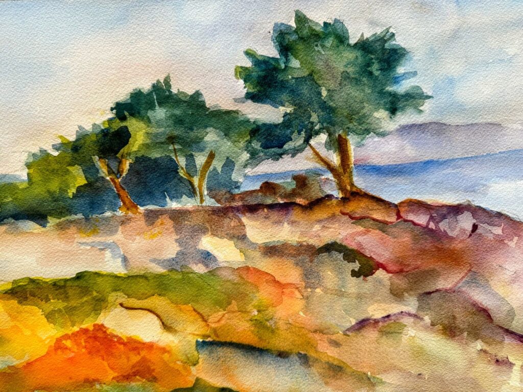 Pacific Grove Cypress, original watercolor painting of three cypress trees at the waters edge with grass and shadows of orange, yellows, tans and greens. There are cloud shrouded hills in the background as well as scattered clouds in the sky above.