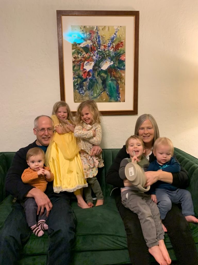 New Years 2025 photo of Eric and Ann Wiegardt with five of their grandchildren sitting on a couch with a painting hanging overhead.